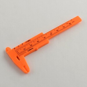 Subler de plastic portocaliu pentru masurarea margelelor 10,5x4,4x0,5cm